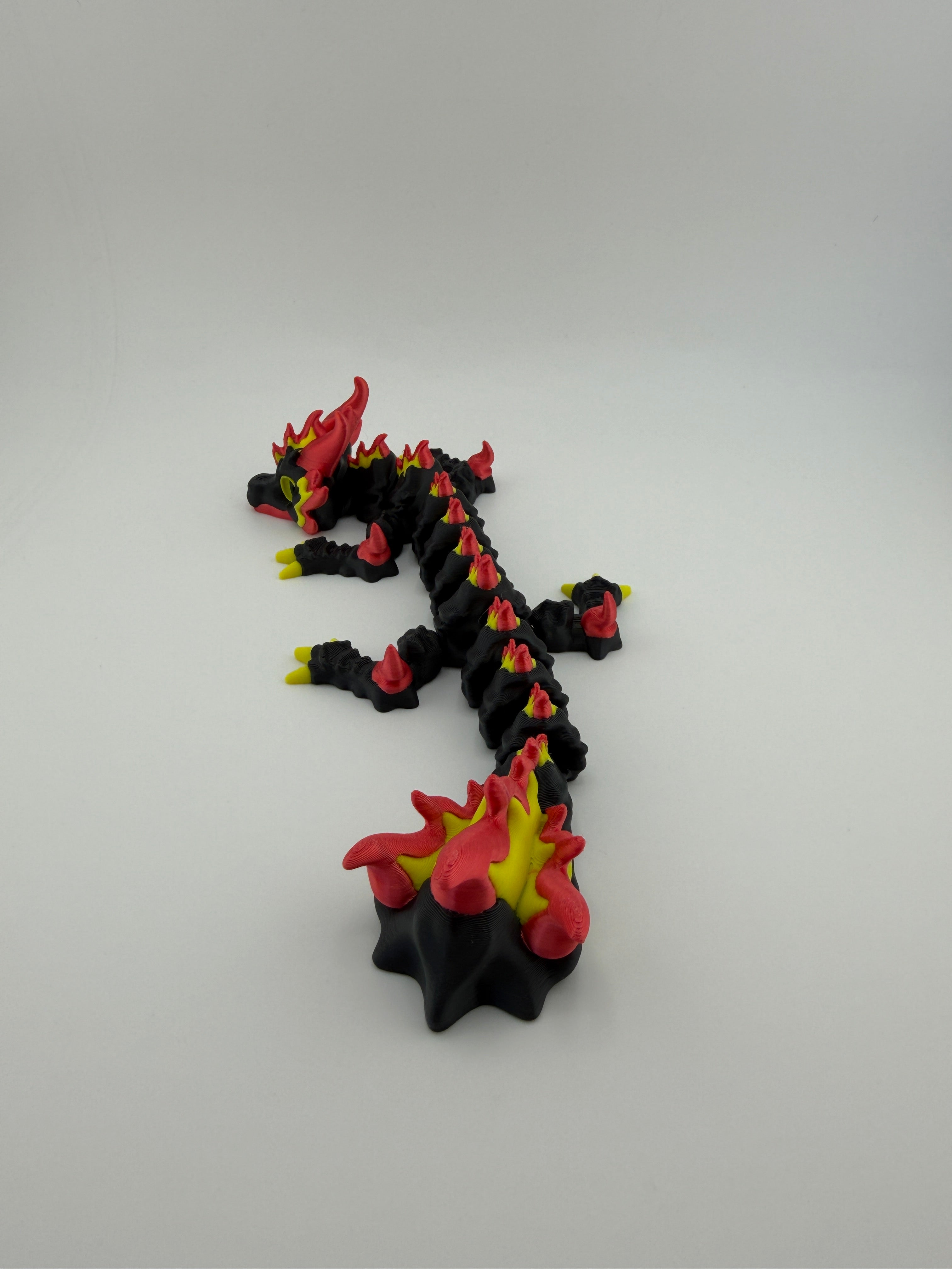 Toy figure of a dragon with black, red, and yellow colors on a white background